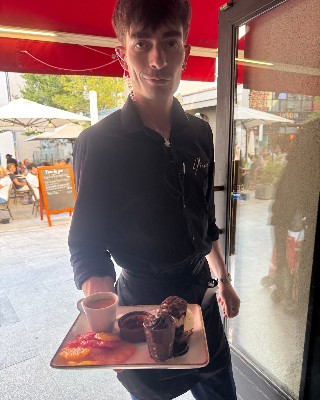 Serveur de L’Annexe apportant un assortiment de desserts gourmands à la terrasse du restaurant