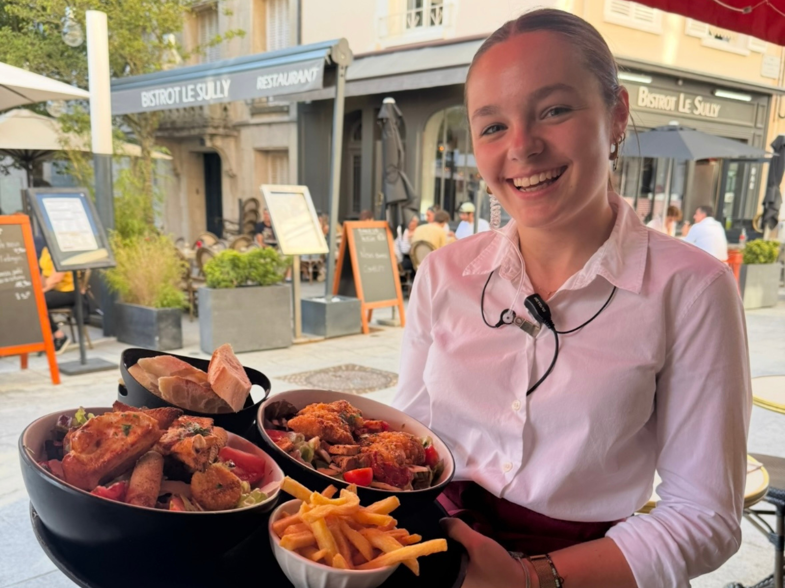 Serveuse souriante avec plats variés et frites maison sur la terrasse de L'Annexe Chartres